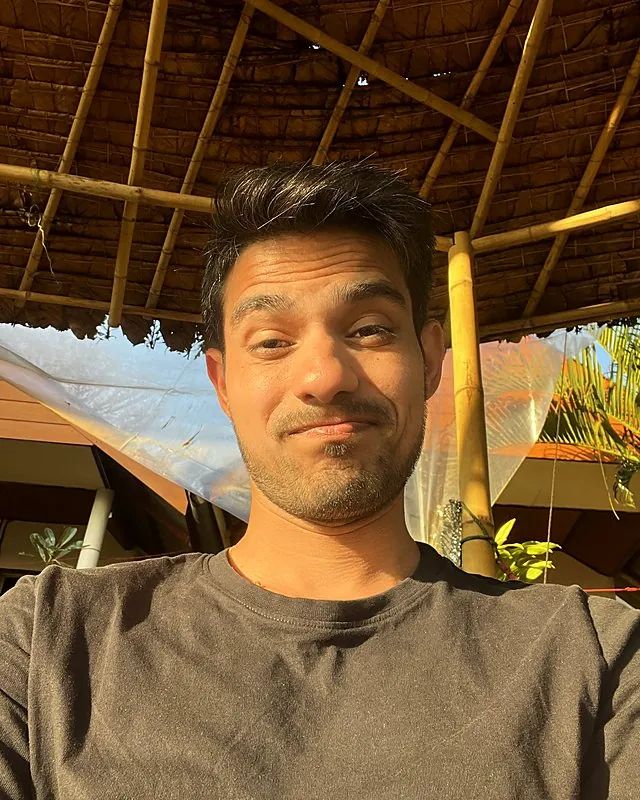Aman smirking in the sun under a thatched roof